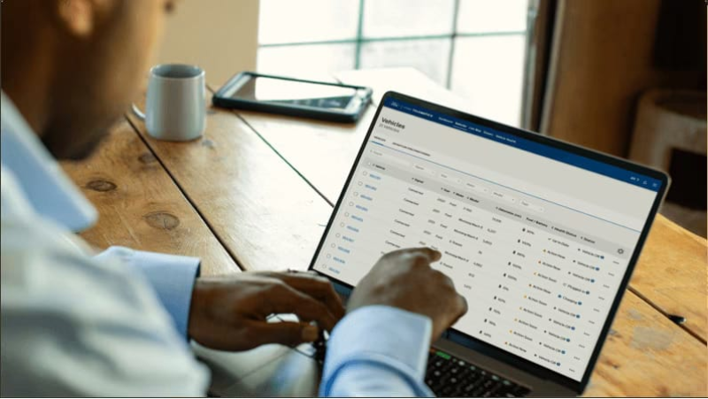 Person working on a laptop displaying vehicle fleet management data at a desk.