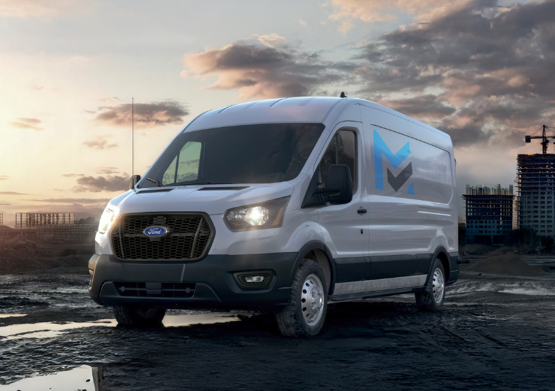 Ford Transit cargo van parked at an industrial worksite during sunset.